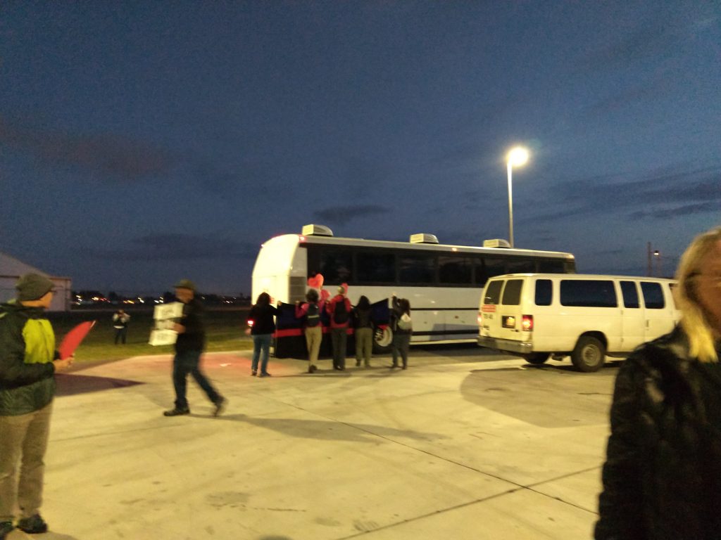 Members of JAIJ join others surrounding a busload of shackled deportees with love, Brownsville-South Padre Airport, Brownsville, Texas, February 14, 2020 (Valentine's Day). Photo by Shel Horowitz.